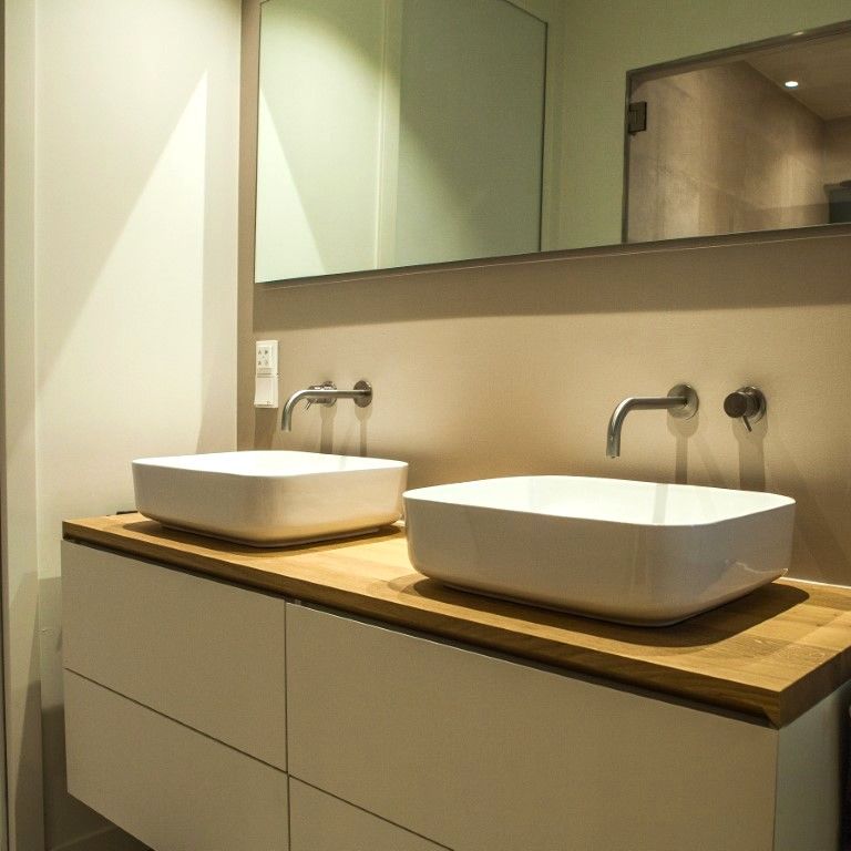 Minimalistisch wastafel met losse kommen op een eikenhouten blad