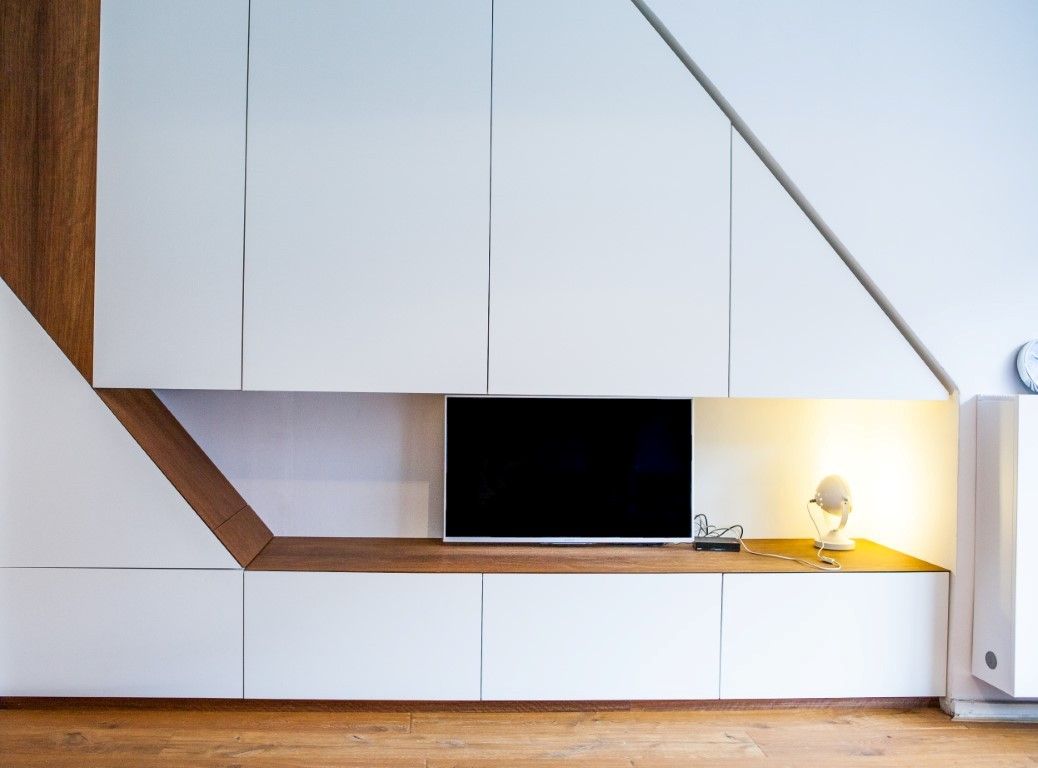 TV-meubel inbouwkast onder een trapopgang in moderne stijl. Diagonale lijnen en strakke vormen. 